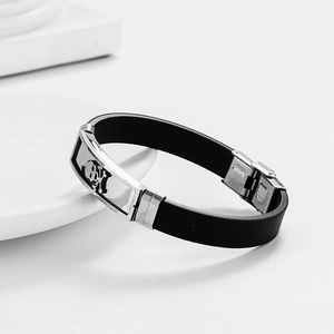 Mens stainless steel and black silicone bracelet featuring a centered skull and crossbones plate