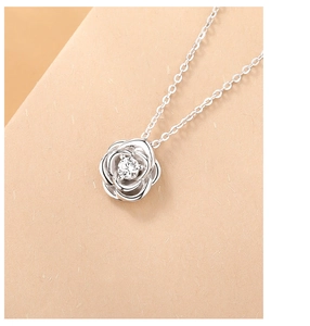 Macro shot of silver rose pendant with sparkling cubic zirconia on a dainty cable chain