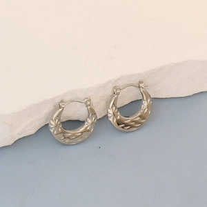 Detailed macro view of vintage silver oval hoop earrings with petal texture pattern