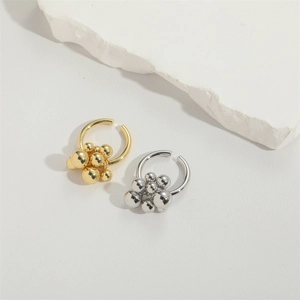 Detailed macro view of minimalist gold and silver bead cluster earrings on stone