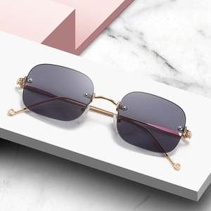 Detail of square rimless sunglasses with gold metal frame on a marble background