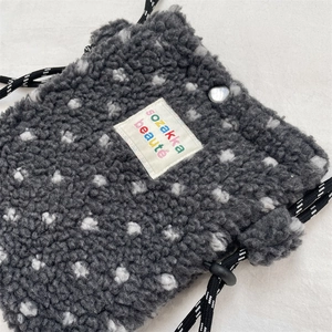 Detail of grey polka dot sherpa crossbody bag featuring woven drawstring and brand label