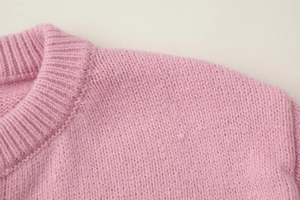 Detail shot showing the ribbed crew neck and fine knit texture of this pink cardigan