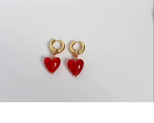 Close-up of red Murano glass heart earrings with gold metal hoops on white background