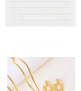 Macro detail of gold-plated titanium earrings with hammered texture and snake chain necklace
