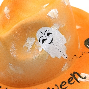 Vue détaillée du chapeau d'Halloween en laine orange avec motifs fantômes et texte festif