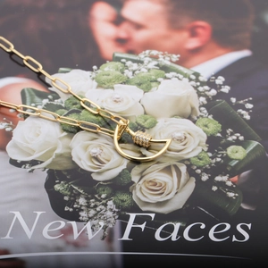 Gold paperclip chain necklace with moon-shaped zircon pendant on a wedding magazine