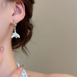 Detail of silver fishtail earring with blue crystal and white pearl on model