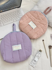 Quilted shell-shaped cosmetic bags in lavender and peach with brand tag and metal zipper