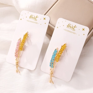 Detail showing wheat stalk brooches with pink, blue, and yellow rhinestones on cards