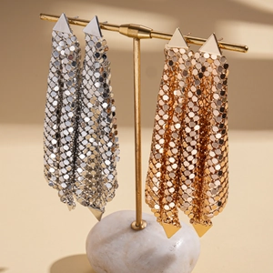 Exaggerated geometric mesh tassel earrings in gold and silver finish on a display