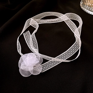 Detail of white mesh lace flower choker with polka dot ribbons on a dark background