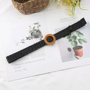 Bohemian black woven belt with a round wooden buckle placed on a botanical magazine