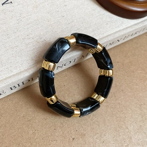 Detail of vintage acrylic bracelet with black marble texture and gold metal spacers