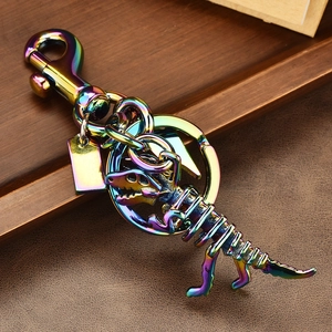 Rainbow dinosaur skeleton metal keychain with carabiner and ring on leather surface
