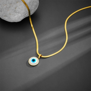 Elegant gold snake chain necklace with sparkling evil eye pendant on stone background