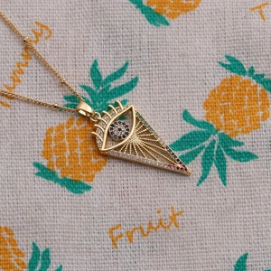 Detailed macro shot of a gold triangle evil eye pendant necklace with colorful zircons