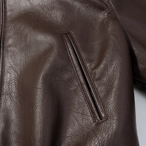 Detail of dark brown leather jacket showing grain texture and side welt pocket design