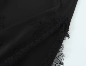 Detail of elegant black satin fabric featuring intricate eyelash lace trim and silk finish