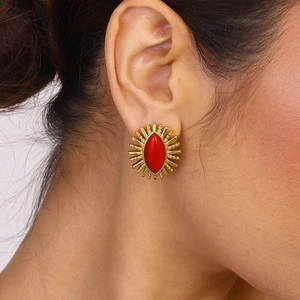 Vintage style gold sunburst stud earrings with red marquise agate stone on a female model
