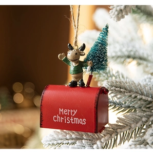 Close-up of red metal mailbox ornament with reindeer and Christmas tree hanging on a branch