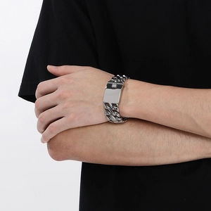 Close-up of a wide 23mm silver braided stainless steel chain bracelet on a model's wrist