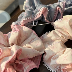 Detailed view of plaid scrunchies with bow print and delicate lace trim in soft colors