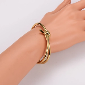 Polished gold minimalist knot bangle bracelet on model at 45-degree angle