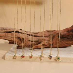 Close-up of assorted gold fruit necklaces with colorful cubic zirconia on a rustic branch