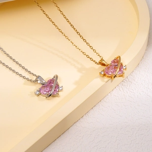 Collier Saturne coeur rose avec cristaux scintillants sur présentoir géométrique