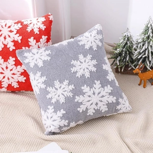 Housses de coussin de Noël en peluche à flocons rouges et gris sur un plaid en tricot