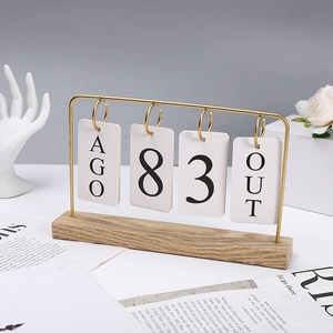 Detail of creative flip calendar with golden metal frame and light wooden base on desk