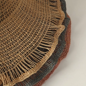 Detail of multi-color raffia sun hats showing intricate woven texture and wavy frayed edges