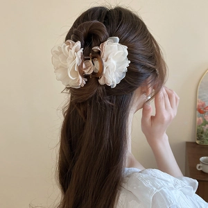Détail d'une élégante pince à cheveux fleur en mousseline crème sur le mannequin