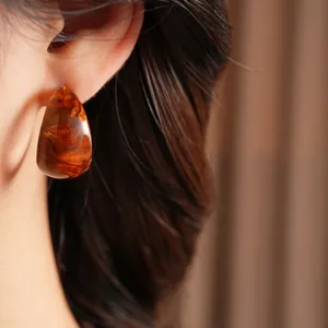 Brown amber resin C-shape hoop earrings with vintage swirl pattern shown on a model