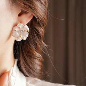 Gros plan d'une boucle d'oreille fleur vintage avec pétales blancs et détails perles