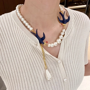 Vintage style asymmetric pearl necklace with blue bird charms and a gold chain pendant
