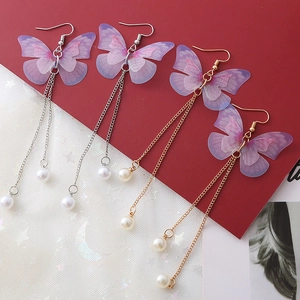 Détails de boucles d'oreilles papillon avec ailes en tulle et pompon de perles