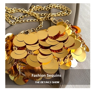 Macro detail of golden circular sequins and fine metal chain strap on evening bag