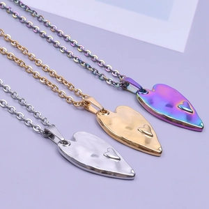 Detailed view of three heart pendants in silver, gold, and rainbow stainless steel