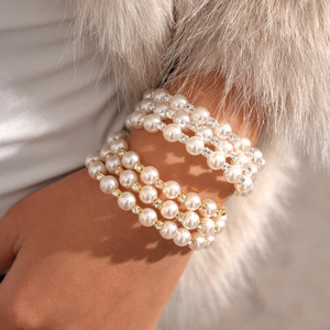 Macro detail of layered pearl bracelet with rhinestones on model with fur luxury background