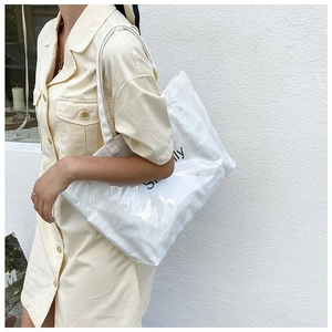 Close-up of white transparent jelly tote bag with Simply print on a model's shoulder