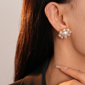 Close-up of vintage flower pearl earrings in gold finish worn by a female model
