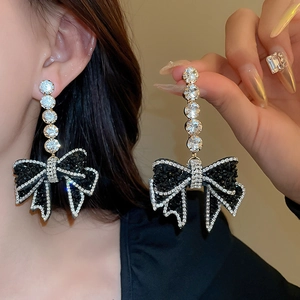 Detailed view of oversized bow earrings with black and white rhinestones on model