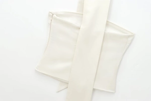Detailansicht eines cremeweißen Satintops mit eleganter Faltung und unsichtbarem Reißverschluss