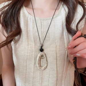 Gros plan détaillé du pendentif ovale en acrylique marbré sur un collier cordon noir