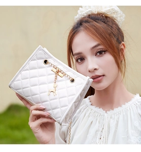White quilted square shoulder bag with gold chain and deer charm shown by a model