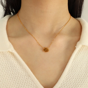 Elegant gold oval tiger eye pendant necklace shown on a white knitted sweater
