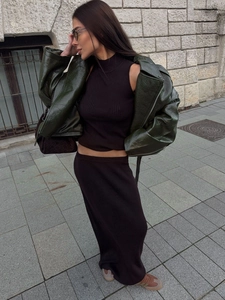 Elegant black knit two-piece set with a halter top and long skirt paired with a green jacket