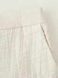 Detailed macro view showing the pleated cotton-linen fabric and elastic waistband texture